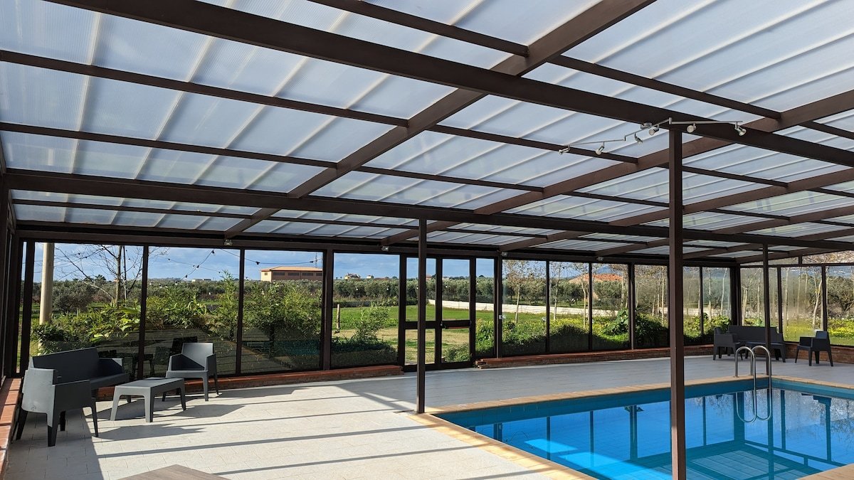 Zona relax accanto alla piscina coperta, con poltroncine e vetrate sulla campagna di Lamezia Terme
