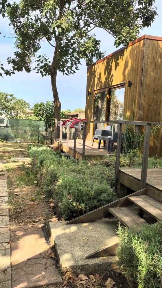 Un bungalow Cubo House con la terrazza in legno, visto dal prato del giardino