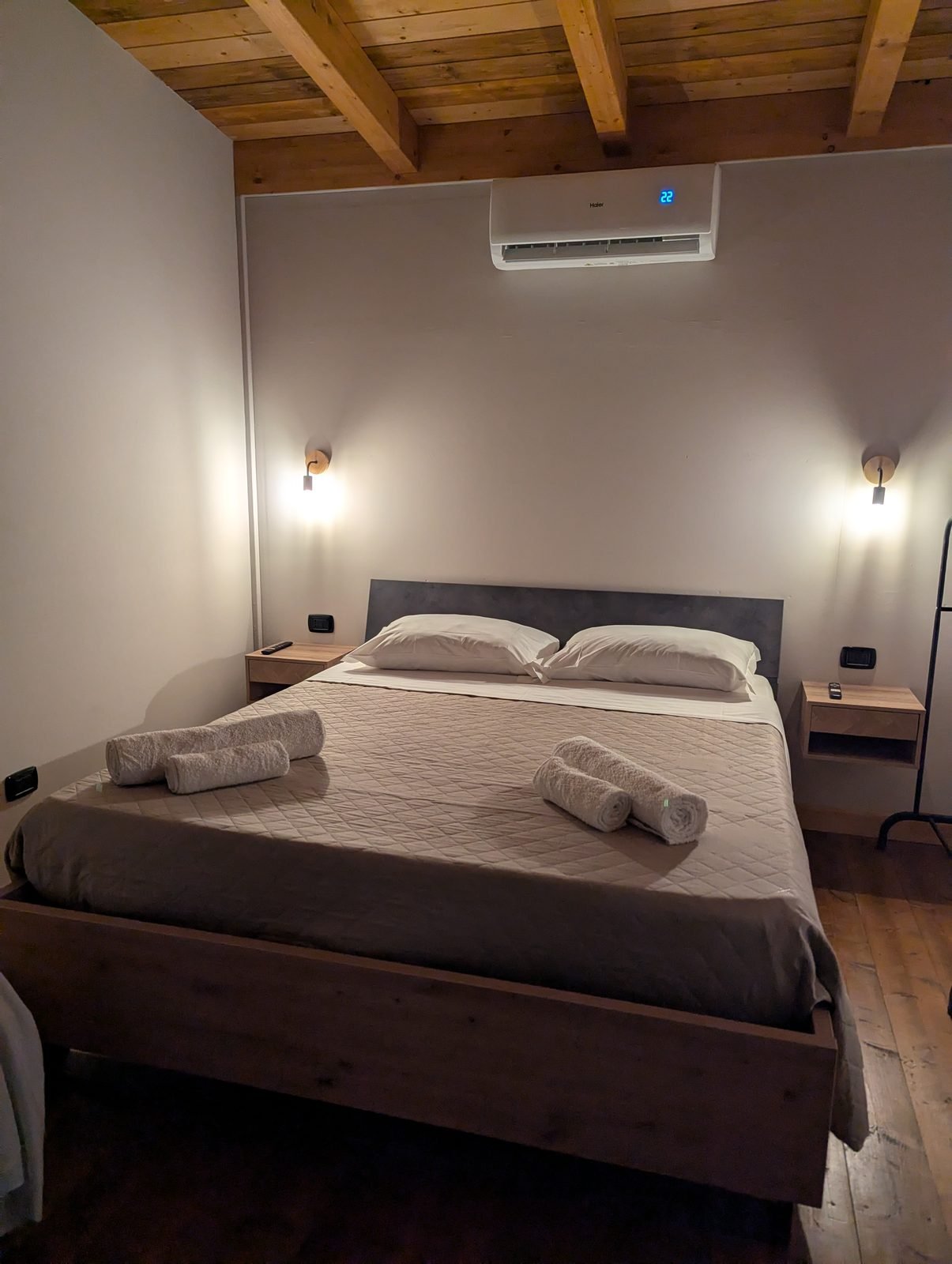 Letto matrimoniale preparato con asciugamani, aria condizionata e soffitto in legno nel bungalow Cubo House