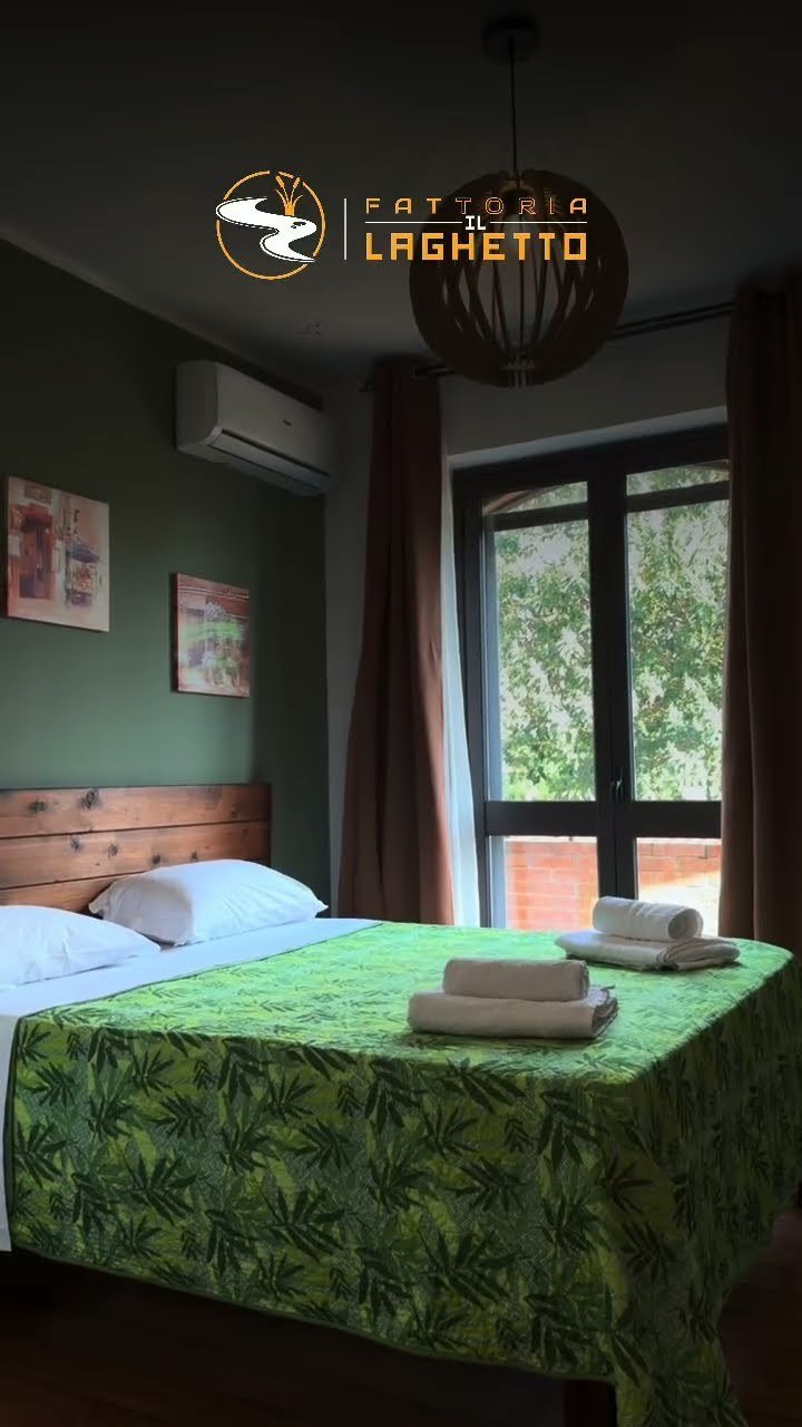 Una camera della Fattoria Il Laghetto, con il letto matrimoniale e la finestra che da sul verde